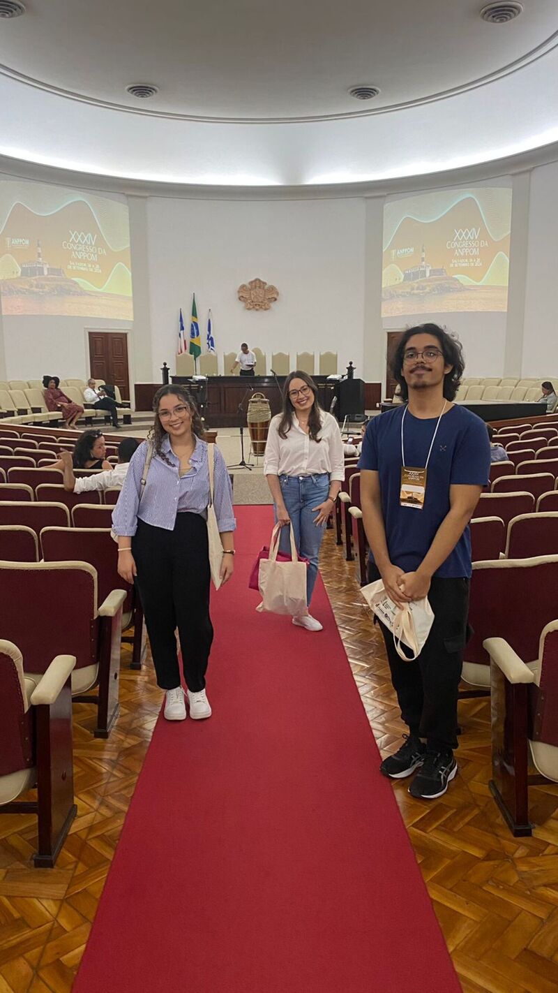 Os estudantes Lívia e Ivan, com a professora Thais na cerimônia de abertura do Congresso da ANPPOM, no Salão Nobre da Reitoria da UFBA.